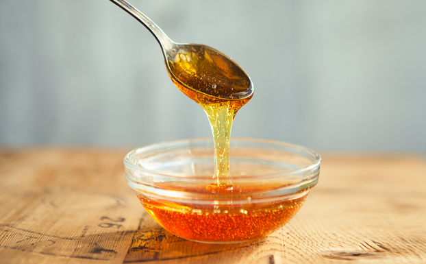 Honey dripping from spoon in the cup in golden sunlight. Source: istockphoto.com. Credit: Olga Trishina